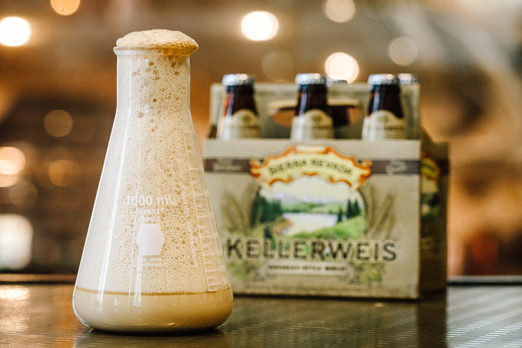 A flask of bubbling Hefeweizen yeast next to a six-pack of Sierra Nevada Kellerweis 