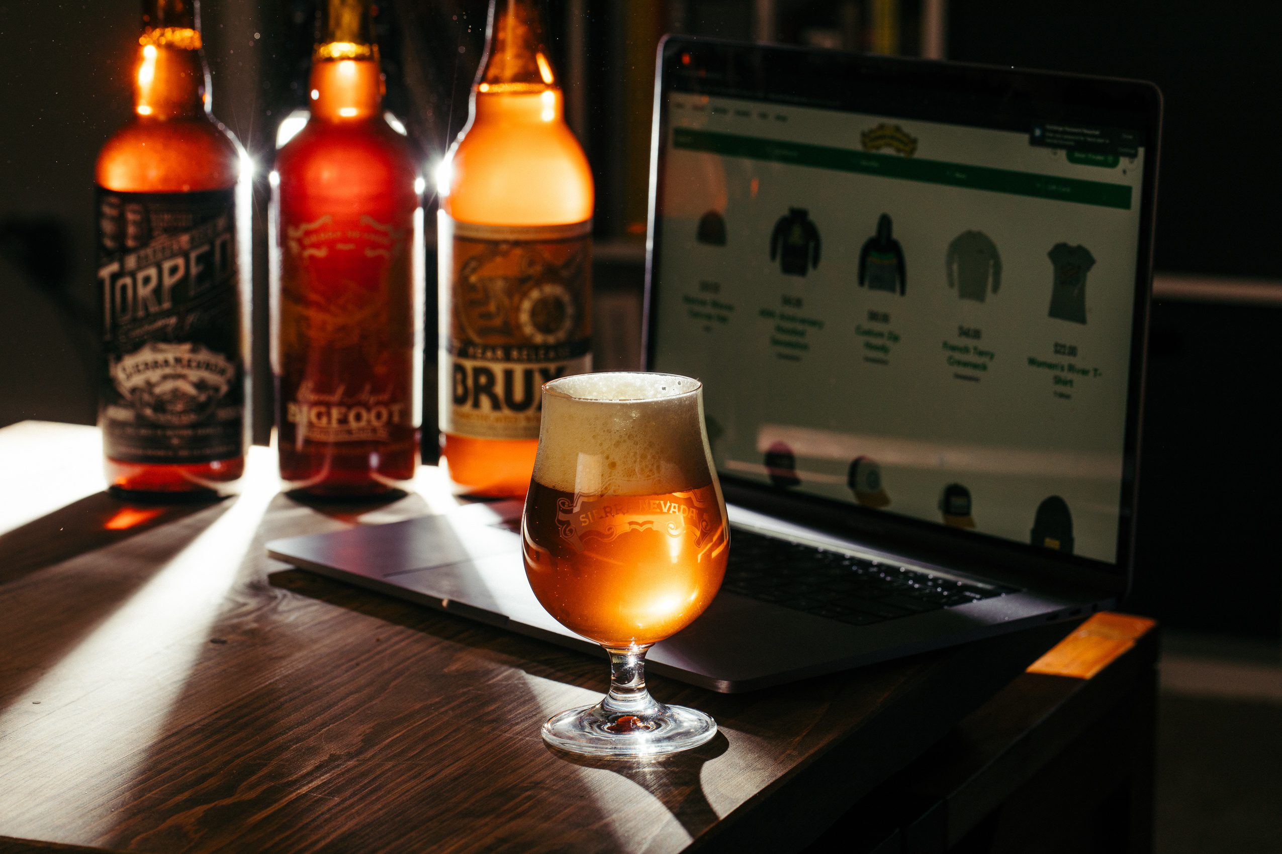 Sun rays shining through several bottles of Sierra Nevada Brewing Company beer and a laptop computer
