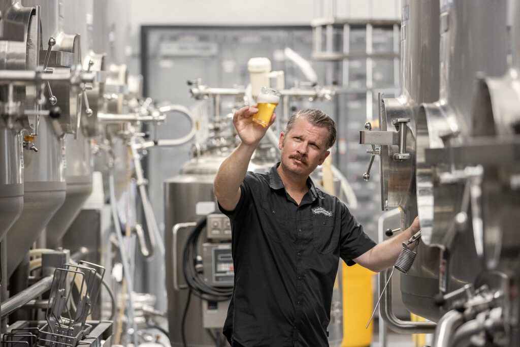 Sierra Nevada brewer holding up a beer to inspect its color and clarity