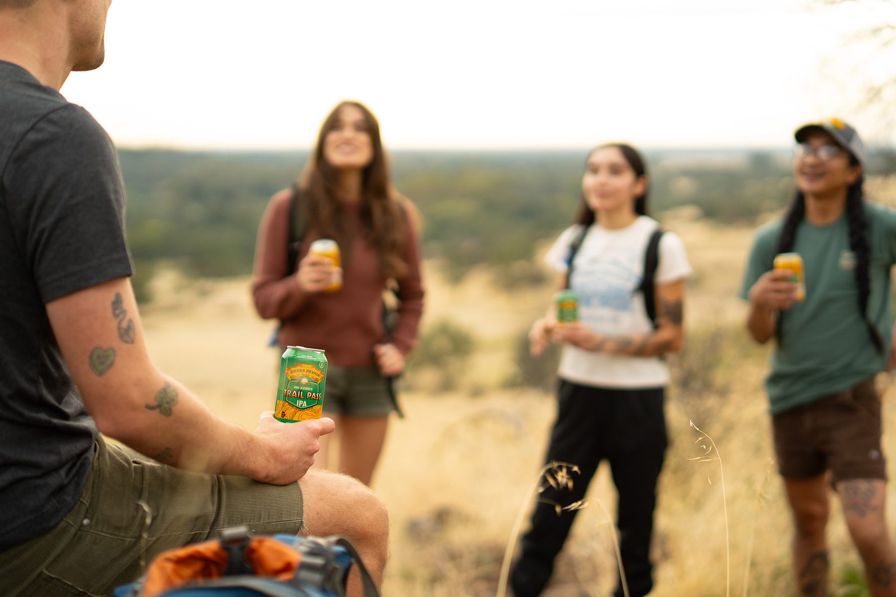 Four friends on a hike take a break to drink cans of non-alcoholic Sierra Nevada Trail Pass brews