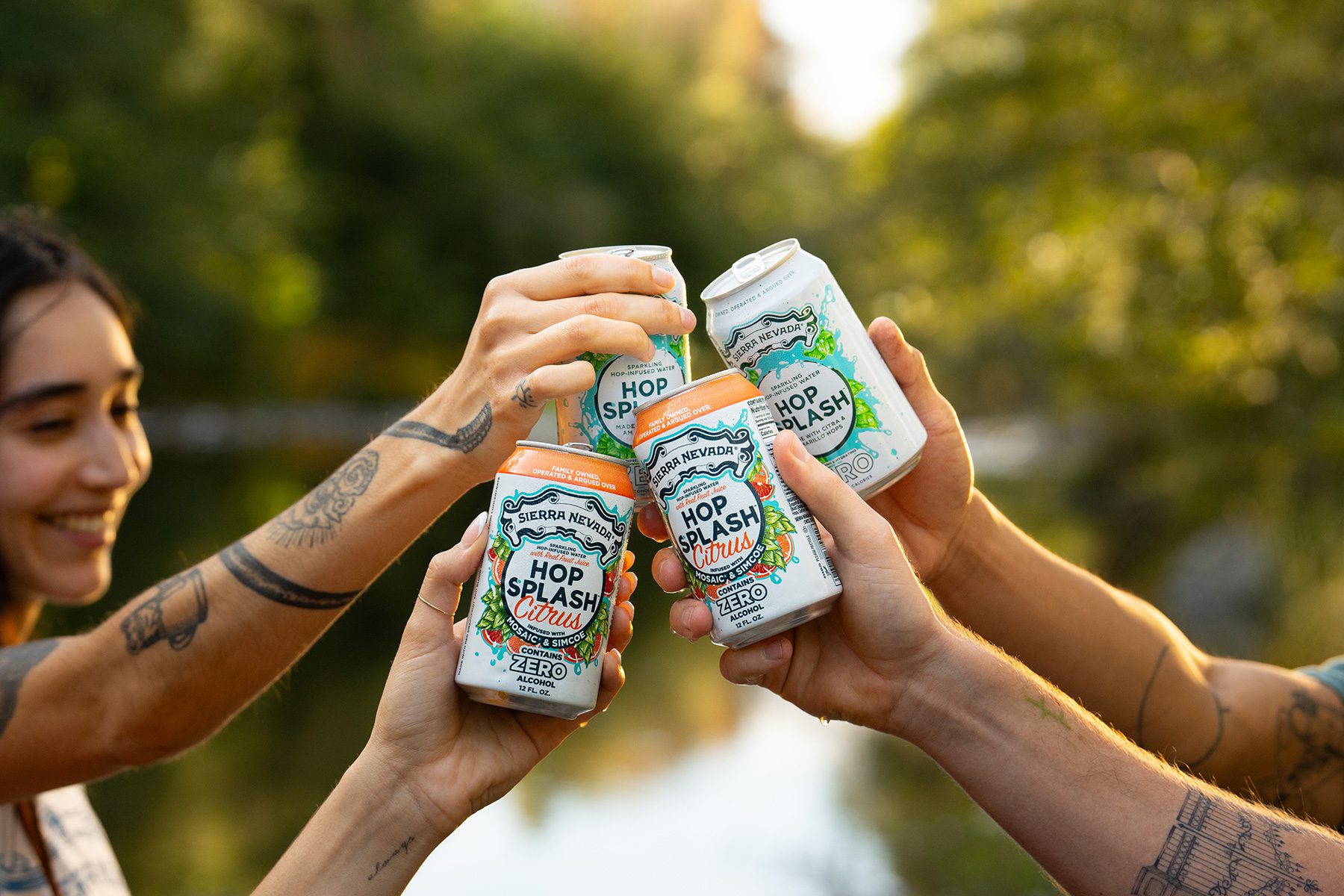 Four friends by a creek holding up cans of Sierra Nevada hop water: Hop Splash and Hop Splash Citrus