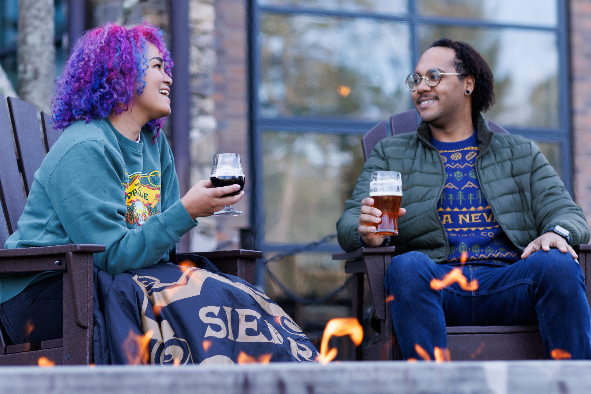 Two friends drinking dark beers around a fire pit