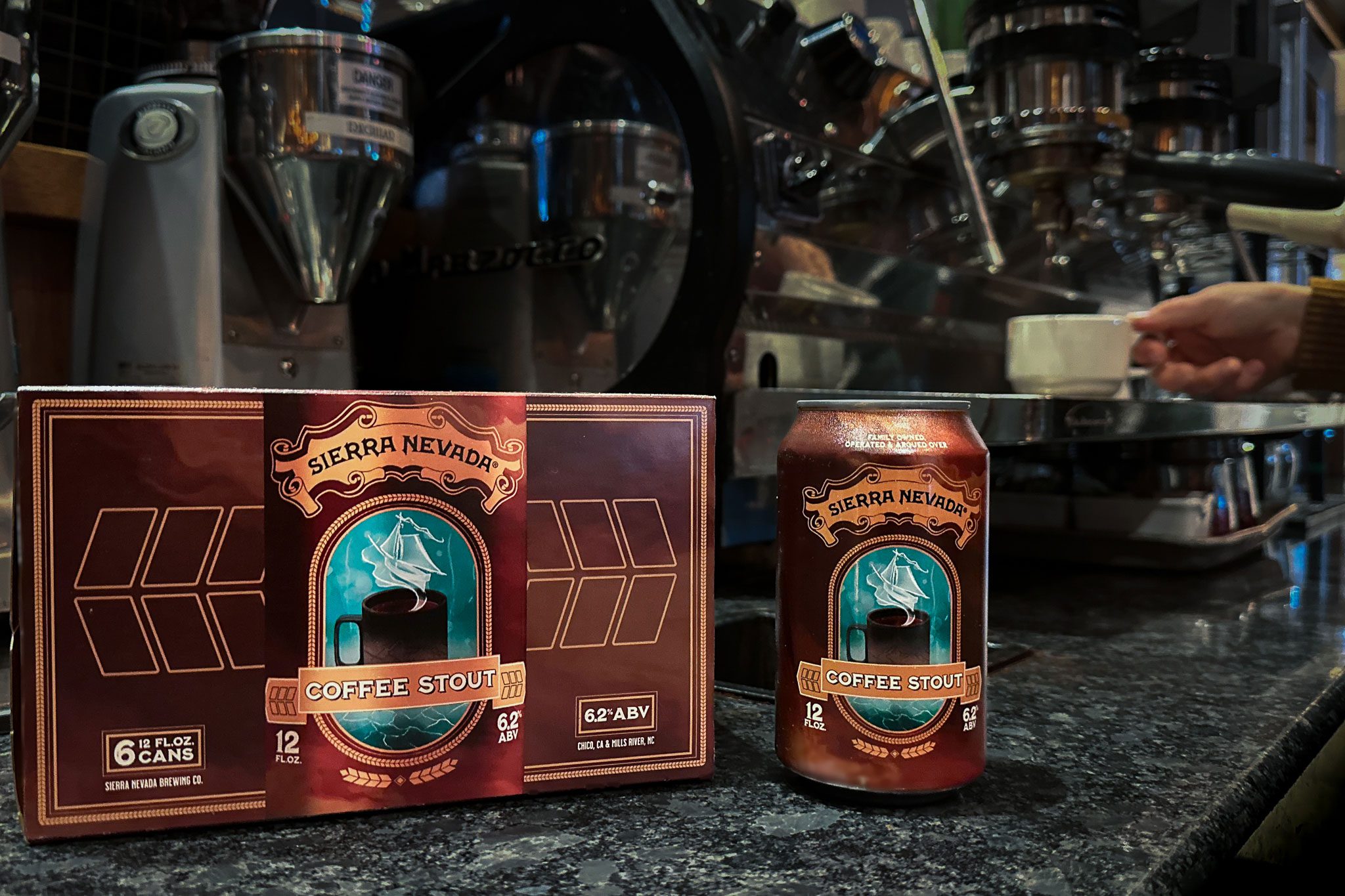 A six-pack and can of Sierra Nevada Coffee Stout in front of an espresso machine