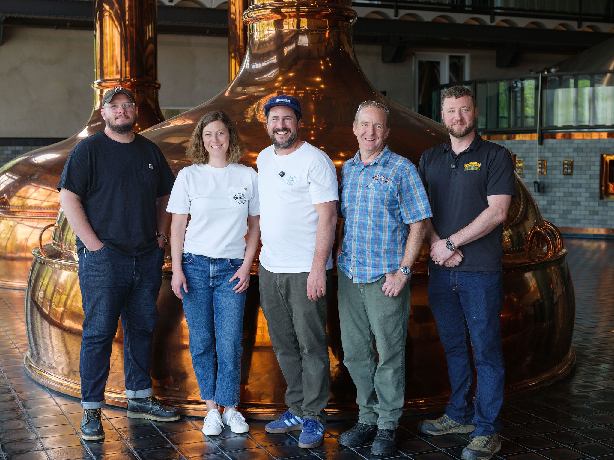 Brewers from Hoppebräu Brewery and Sierra Nevada Brewing Co. standing in front of a copper brew kettle